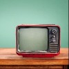 Retro red television on wood table with vintage aquamarine wall background