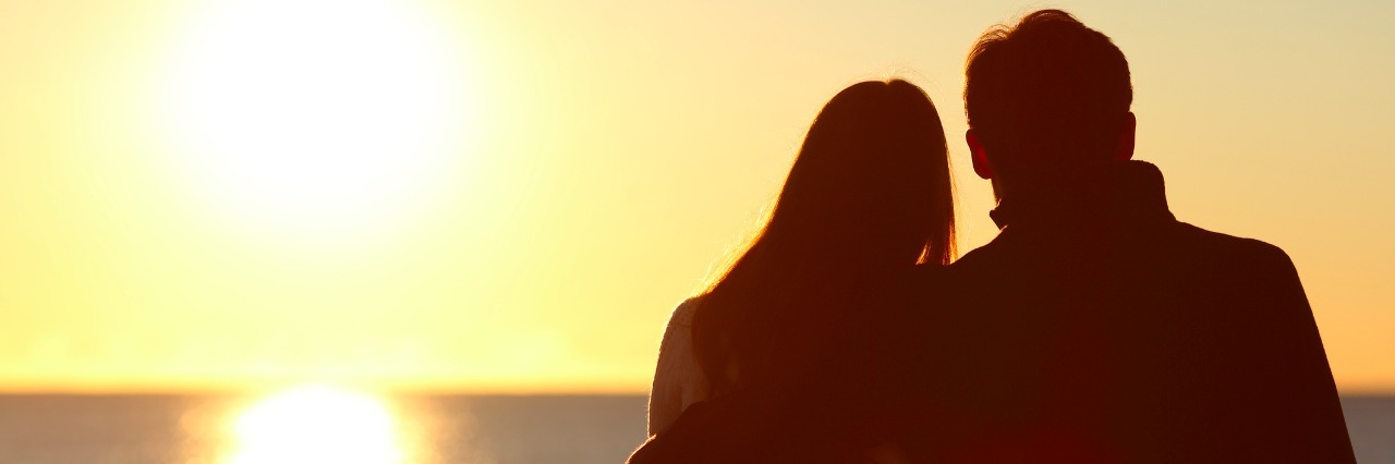 A Letter to Friends Who Didn't Know Me Before My Chronic Fatigue Back view of a couple silhouette hugging and watching sun on the beach