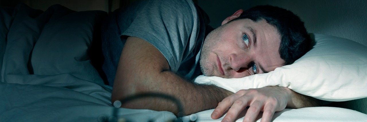 Depression: When Negative Thoughts Keep You Up at Night man in bed eyes opened suffering insomnia and sleep disorder