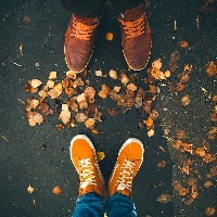 close-up of two people's shoes as they stand in front of one another, with fall leaves at their feet