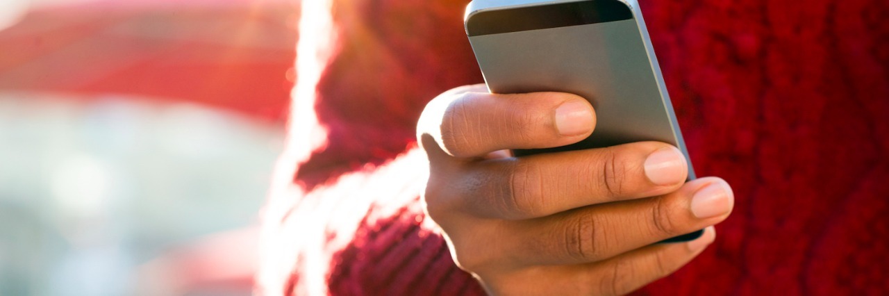 Close-up of person wearing red sweater, holding cell phone in one hand