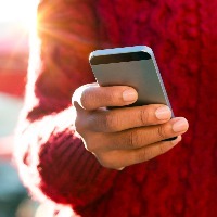 Close-up of person wearing red sweater, holding cell phone in one hand