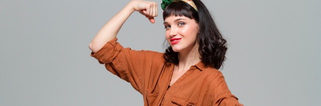 positive happy young woman showing biceps isolated over grey background