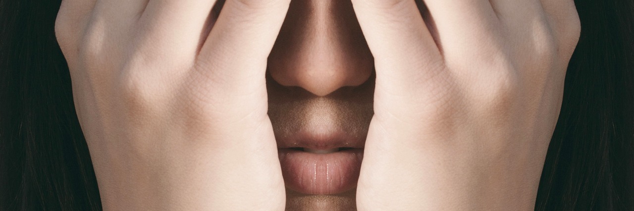 Good Things About Living With Anxiety Mirrored photograph of a woman hiding here face