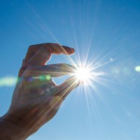 A hand stretched out, so it looks like it's holding the sun