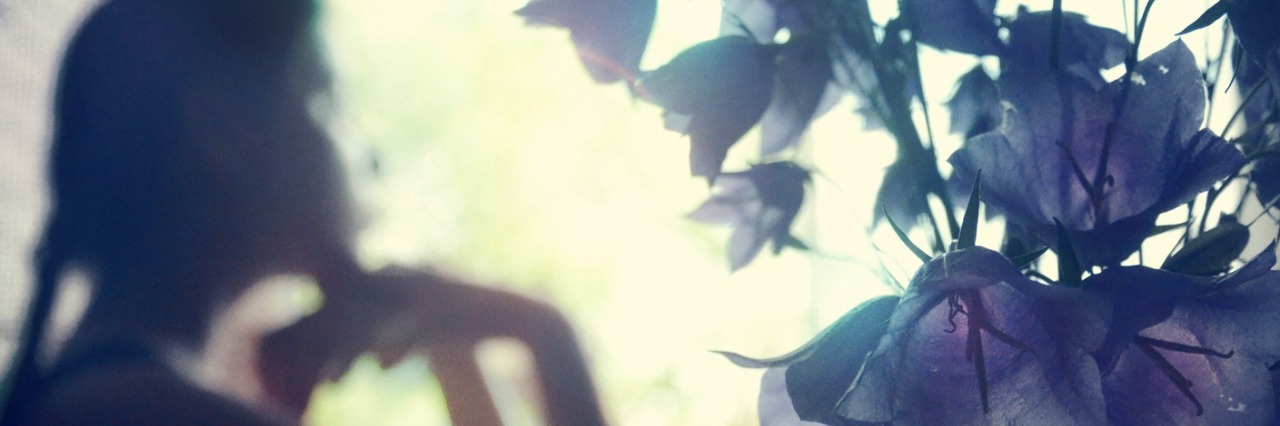 Crohn's Disease: Coping With People Leaving You woman staring out of a window next to a vase of purple flowers
