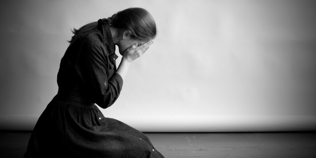 grieving woman on her knees with her face in her hands