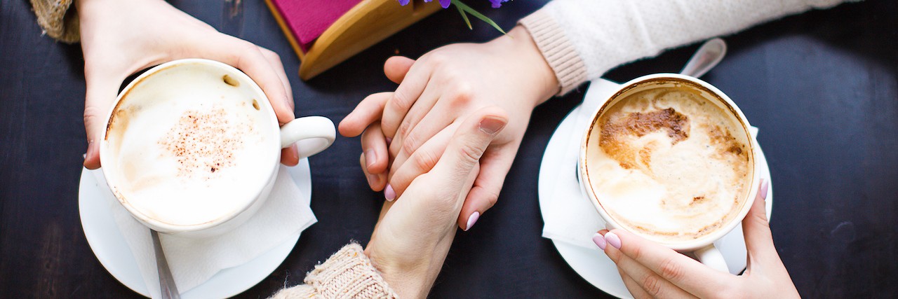two people drinking coffee and holding hands
