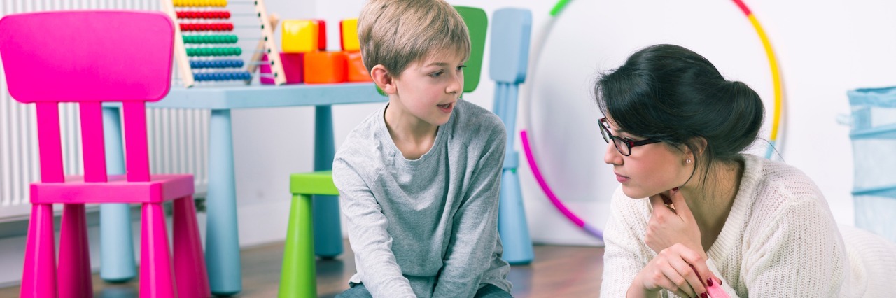 How to Choose a Therapist for Your Child Child and teacher or therapist drawing with chalk on floor