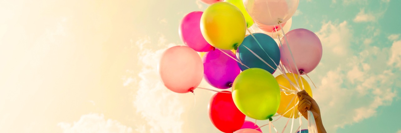 The Silver Lining in Chronic Pain Girl hand holding colorful balloons. happy birthday party. vintage filter effect