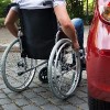 Man in a wheelchair near car.
