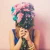 woman holding a bouquet of colorful flowers in front of her face