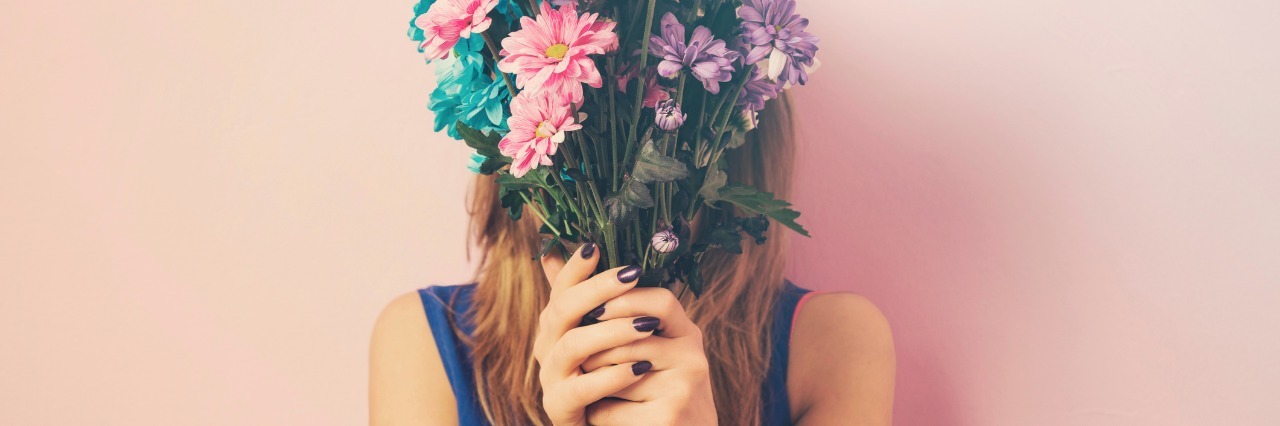 How Crohn's Disease, Endometriosis Made Me a Better Person woman holding a bouquet of colorful flowers in front of her face