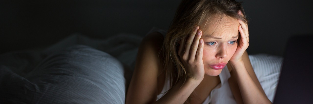 Dealing With Pain and Insomnia With Rheumatoid Arthritis woman looking at laptop at night in bed