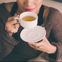 woman holding a hot cup of tea and blowing on it
