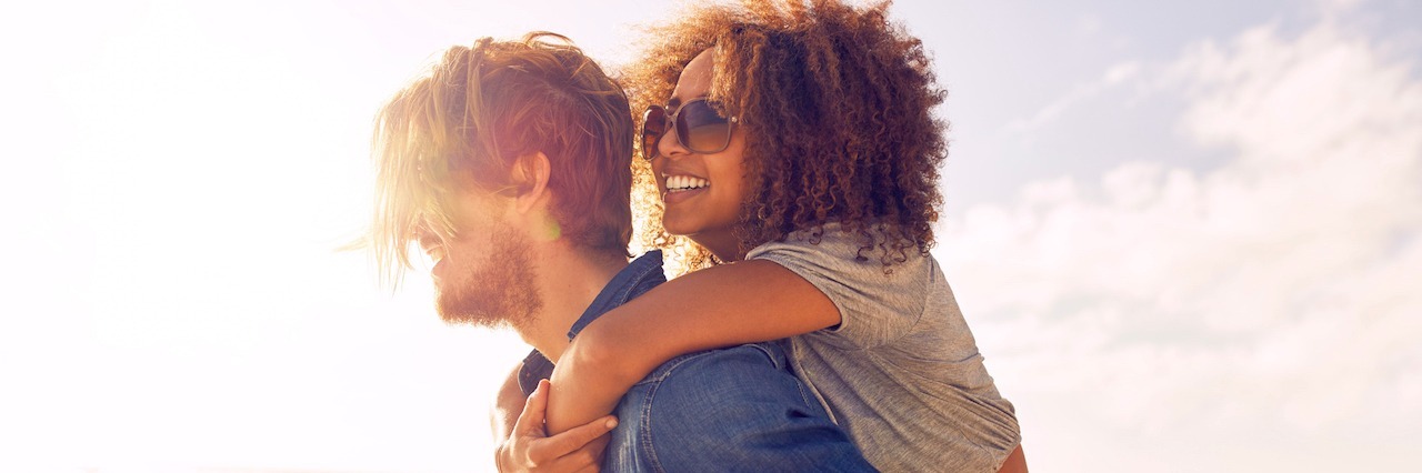 10 Things You Should Know If Your Partner Has Anxiety A man giving a piggy-back right to his girlfriend on the beach