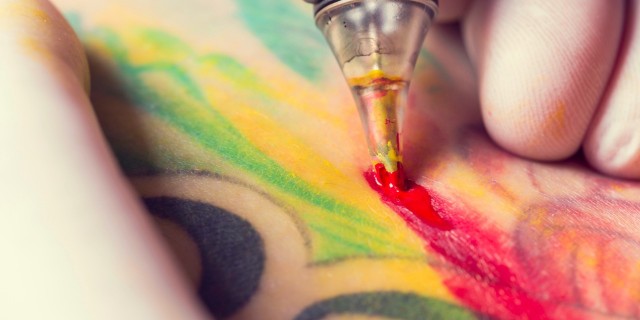 Tattoo artist applying tattoo to someone's skin