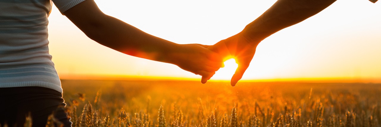 The Anxiety I Feel After My Son Died by Suicide Young couple holding hands in the wheat field on sunny summer day.