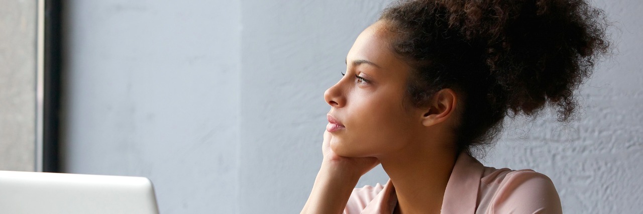 Why I Struggle on the Anniversary of My RSD Diagnosis Close up portrait of a young woman looking out window when working on laptop