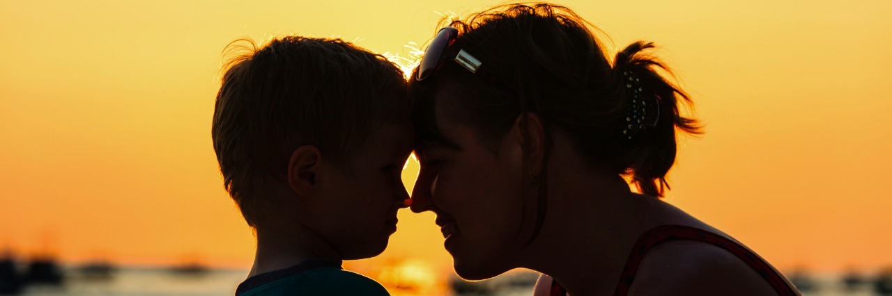 happy loving mother and little son at sunset beach