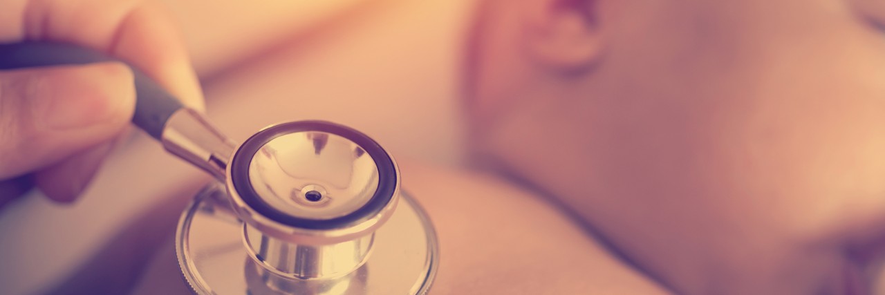 To the Doctor Who Diagnosed My Son With Down Syndrome Pediatric doctor exams newborn baby girl with stethoscope in hospital