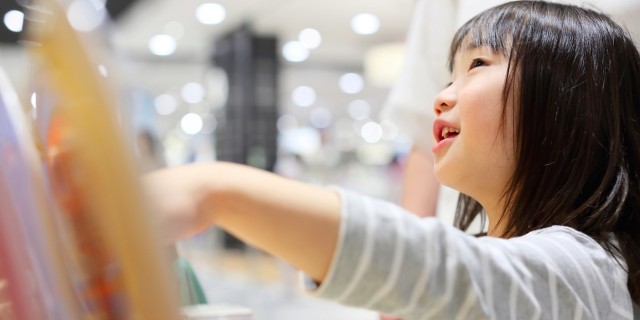 Girl pointing at item behind glass case at supermarket