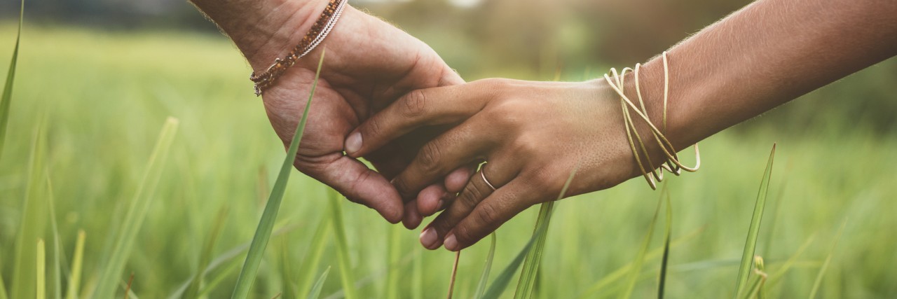 Romantic couple holding hands in a field.