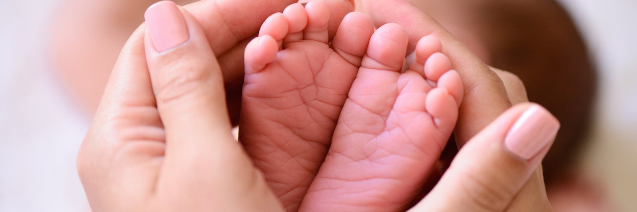 How Postpartum Depression Led Me to a Place Of Gratitude Mother holding tiny foot of newborn baby