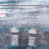 Pair of sneakers on pavement with digital glitch effect, young adult man standing on concrete flooring