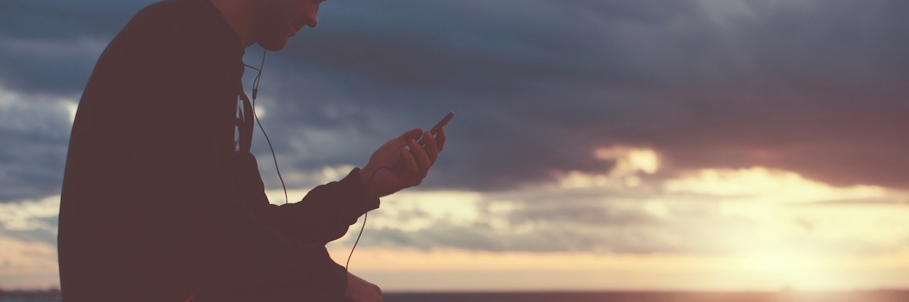 A man sitting on a ledge listening to music