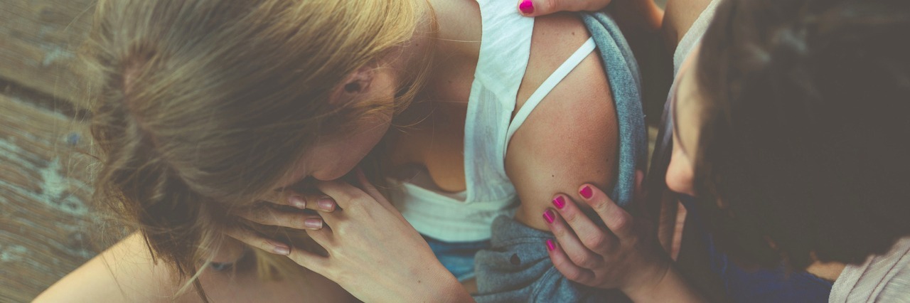 Woman helping her friend sitting on the ground