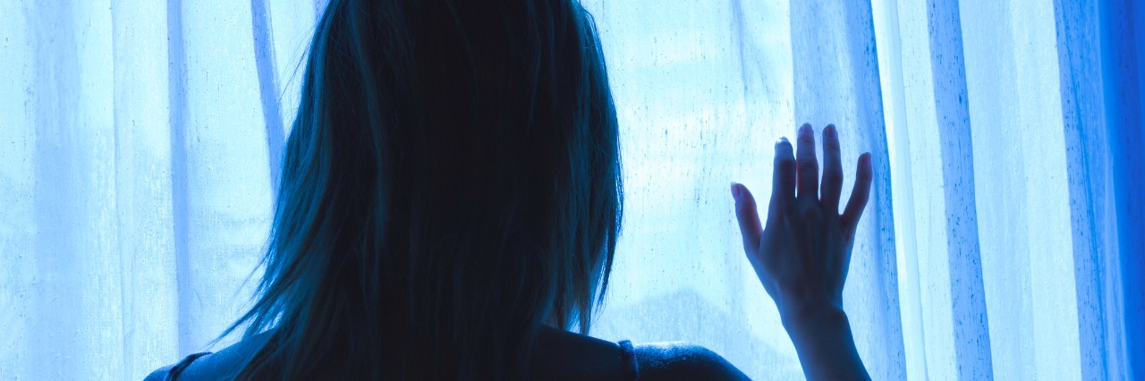 What Two Hours Feel Like With Chronic Pain Lonesome girl holding a curtain at night looking out window