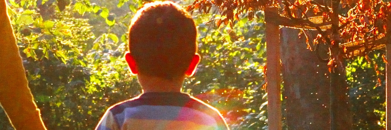 Boy wearing striped shirt, walking in park holding mom's hand on sunny day
