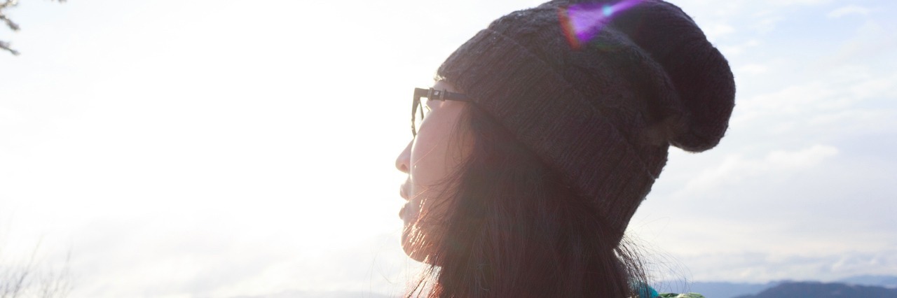 How I Manage My Anxiety A woman wearing a hat looking back at a mountain