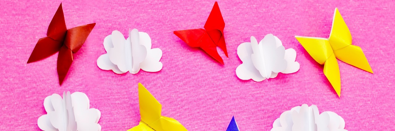 Pink background with paper multicolored butterflies and clouds. toning. selective focus