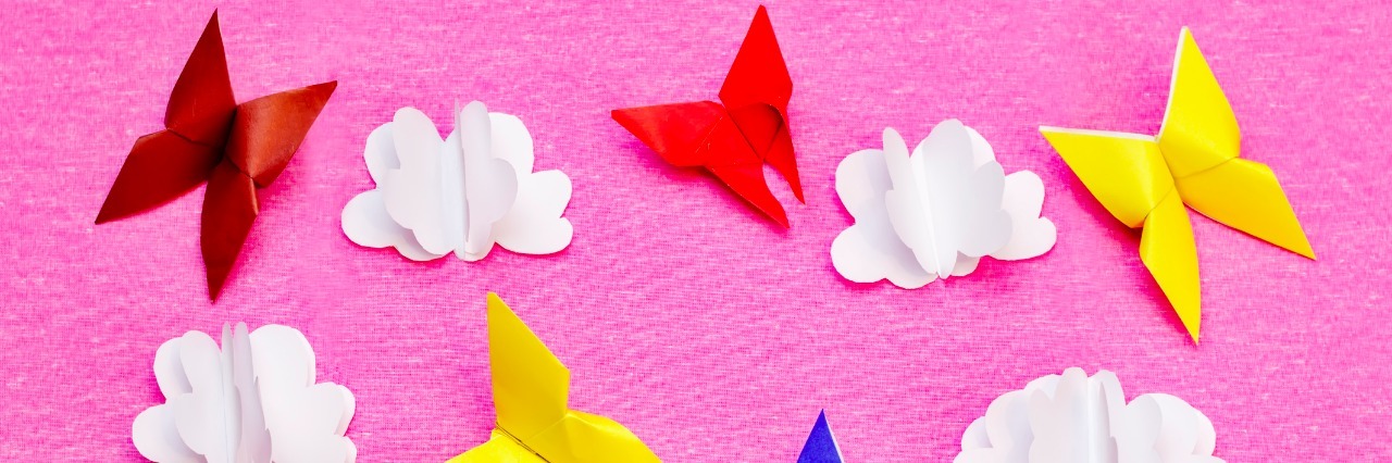 The Realities of Life With Ehlers-Danlos Syndrome Pink background with paper multicolored butterflies and clouds. toning. selective focus