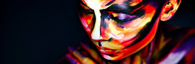 woman's face and arms covered in multicolored paint