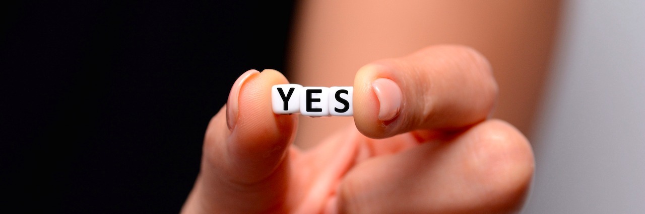 Daily Reminders for People With Mental Illness A woman holding small blocks that spell out YES