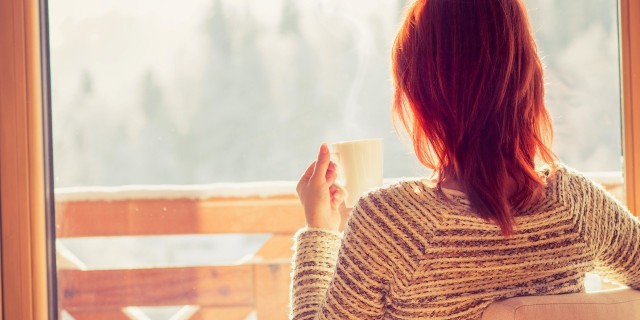 What 'Quality of Life' Means to Me as I Adapt to Cancer Woman sitting in a comfortable chair drinking coffee and looking through window at snow covered mountain.
