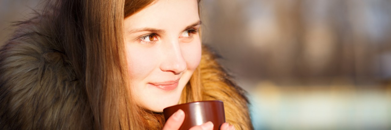 Young girl holding cup of coffee in winter park