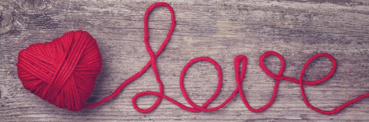 Red heart of red wool yarn on a wooden background