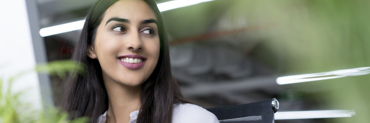 Mental Health Advocacy Is My Purpose in Life Portrait of young Latin-American businesswoman sitting at computer in office, looking away and smiling