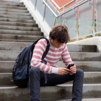 teen sitting on steps, looking at this phone