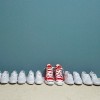 Pair of shoes in row against wall, all white and one red