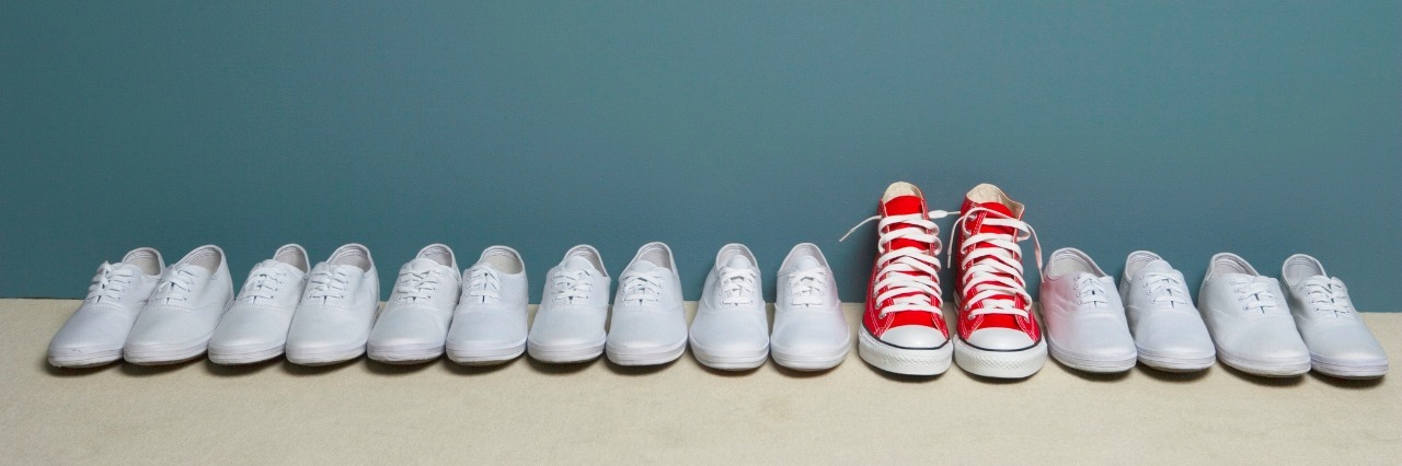 Pair of shoes in row against wall, all white and one red