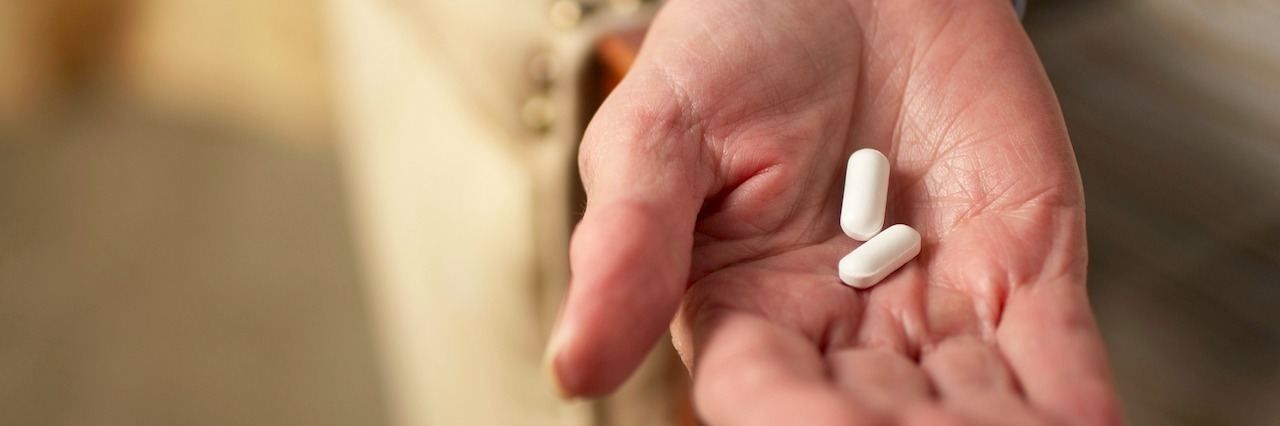 When It's Hard to Convince Yourself to Take Antipsychotics A woman holding pills in her hand