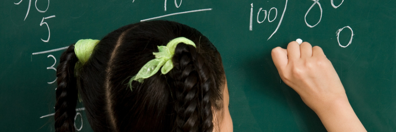 Responding to a Teacher Who Judged Me for My Hearing Loss Girl writing on blackboard.