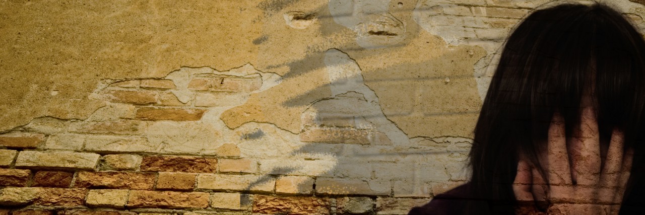 When Panic Attacks Convince You You're Dying woman crying near a brick wall