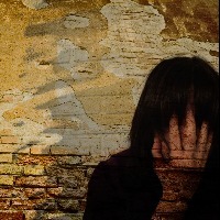woman crying near a brick wall