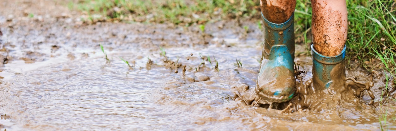 Lessons From Childhood Bullying Due to a Limb Difference Child's feet stomping in a mud puddle.